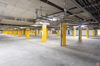 A large, empty parking garage with yellow poles and concrete floors.